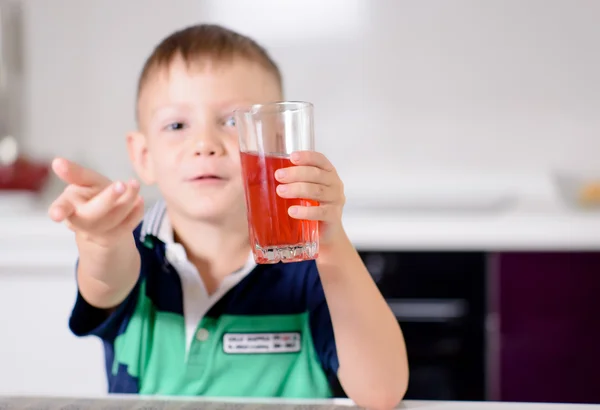 カメラに向かって赤いジュースのガラスを保持している少年 — ストック写真