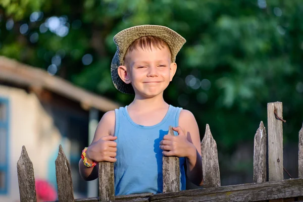 Vrolijke jonge jongen bedrijf aan de houten hek — Stockfoto