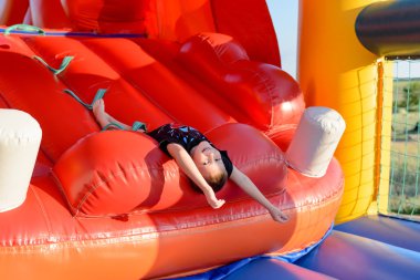 Çocuk (7-9 yaş) baş aşağı bouncy kale üzerinde yatıyor