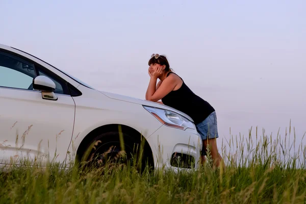 Женщина опирается на автомобильную шапочку и наслаждается видом на закат — стоковое фото