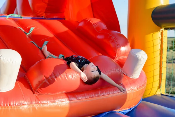 Menino (7-9 anos) encontra-se de cabeça para baixo no castelo bouncy — Fotografia de Stock