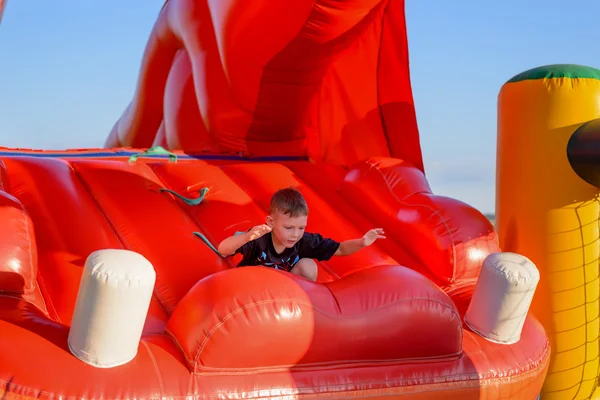 Menino pequeno (6-8 anos) joga no castelo bouncy — Fotografia de Stock