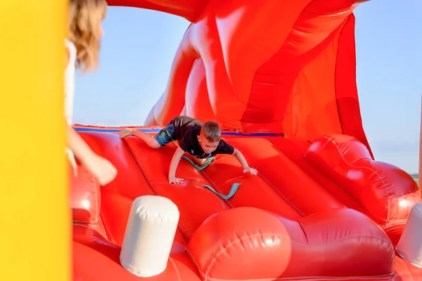 Menino pequeno (7-9 anos) embaralha no castelo bouncy — Fotografia de Stock