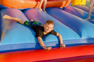Small blonde boy lying on bouncy castle