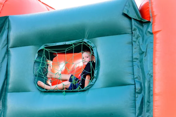 Small boy sitting in window of bouncy castle — Stockfoto