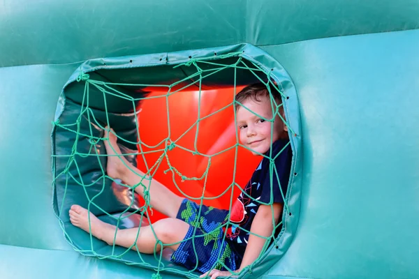 Small boy sitting in window of bouncy castle — Stockfoto