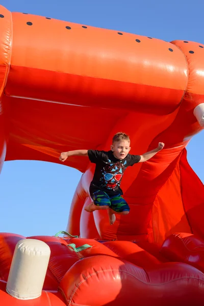 Giovane ragazzo che salta su un castello di plastica salto — Foto Stock