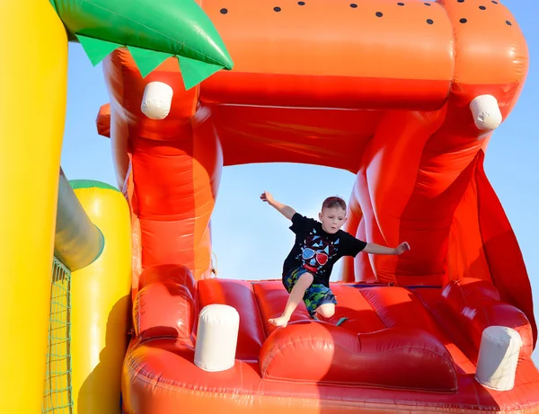 Giovane ragazzo che salta su un castello di plastica salto — Foto Stock