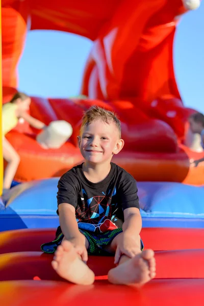 Usměvavý chlapeček sedí na skákací hrad — Stock fotografie