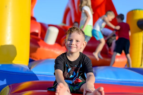 Smiling little boy sitting on a jumping castle — Stock Photo, Image