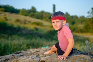 Athletic Boy Doing Side Planking on Top of Boulder