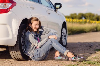 Thoughtful Girl Leaning Against Vehicle Tire