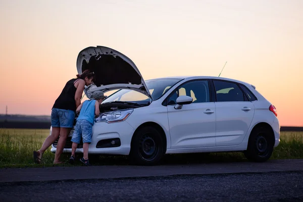 Mãe com filho abrindo a frente do carro defeituoso — Fotografia de Stock