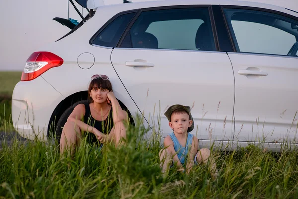 Mãe e filho se senta ao lado do carro enquanto espera — Fotografia de Stock