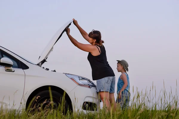 Mamá con hijo abriendo la parte delantera del coche defectuoso — Foto de Stock