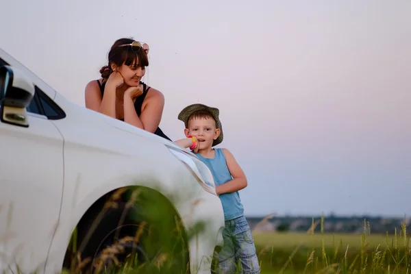 Mãe e filho se apoiando na frente do carro branco — Fotografia de Stock