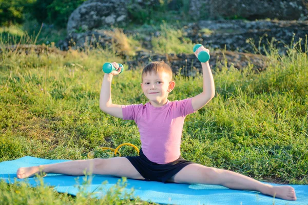 Smiling Kid Lifting Weights While Spliting Legs — стоковое фото