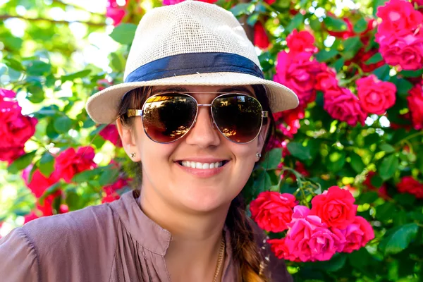 Donna sorridente contro pianta graziosa del fiore rosso — Foto Stock