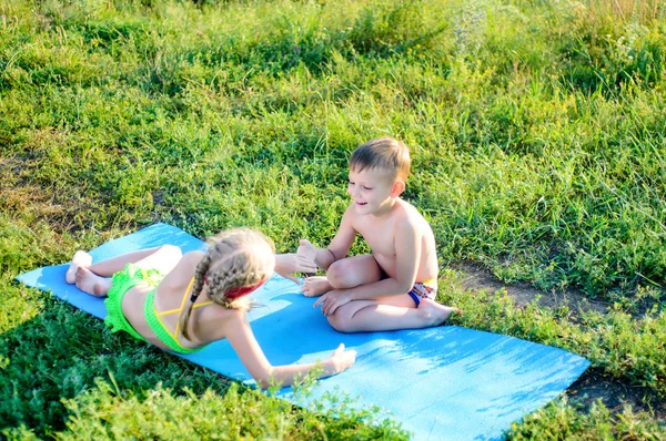 Šťastné roztomilé děti mazlení na matraci na trávy — Stock fotografie