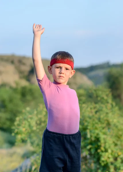 Kleiner Junge mit Stirnband, der seinen einen Arm hebt — Stockfoto