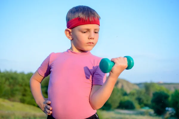 Forte ragazzo in un esercizio all'aperto sollevamento Dumbbell — Foto Stock