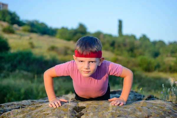 Sportig unga pojke gör driva upp på toppen av Boulder — Stockfoto