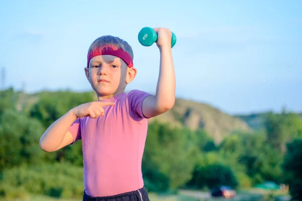 Boy Lifting Dumbbell and Pointing his Arm Muscles — Zdjęcie stockowe