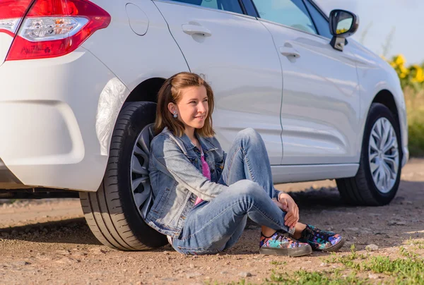 Fille réfléchie appuyé contre un pneu de véhicule — Photo