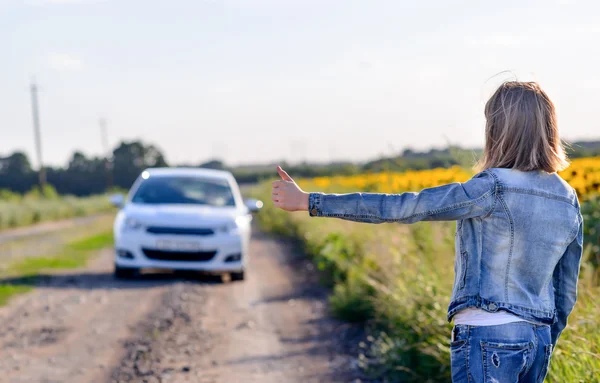 Meisje Thumbs up een auto de weg tonen — Stockfoto