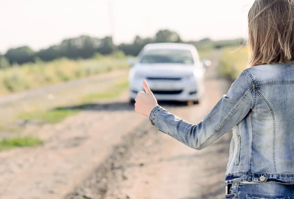 Młoda kobieta autostopem na wsi — Zdjęcie stockowe