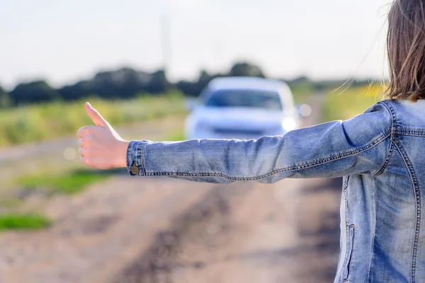 Young woman hitchhiking in the countryside — Stock Photo, Image
