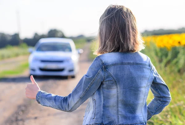 Mulher carona em uma estrada rural — Fotografia de Stock