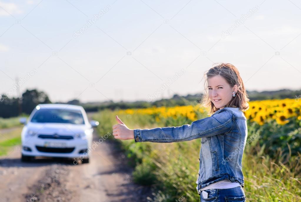Young woman hitchhiking in the countryside