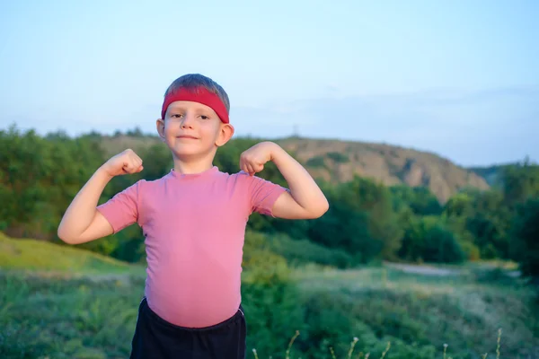 Liten pojke visar upp sin biceps — Stockfoto