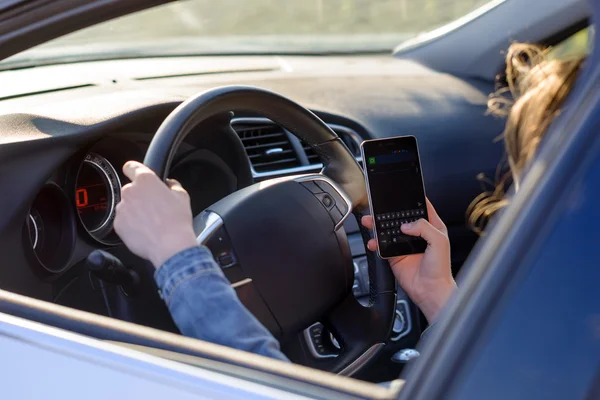 Frau fährt Auto, als sie eine SMS liest — Stockfoto