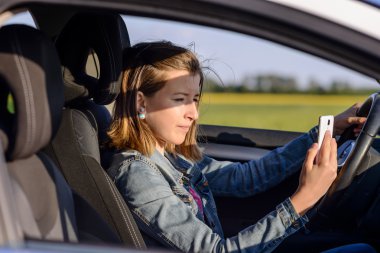 Young female driver reading a text message clipart