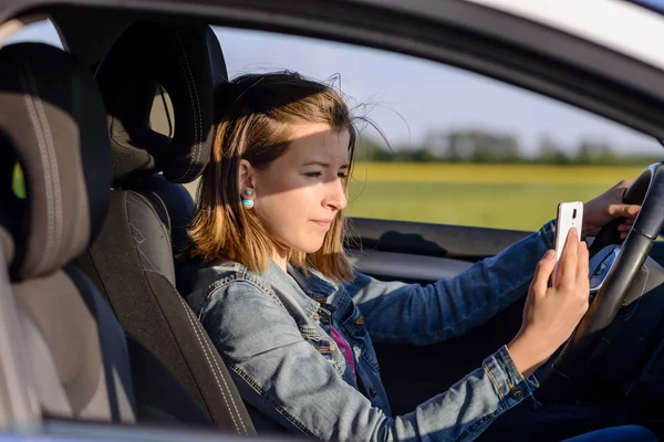 Junge Autofahrerin liest eine SMS — Stockfoto