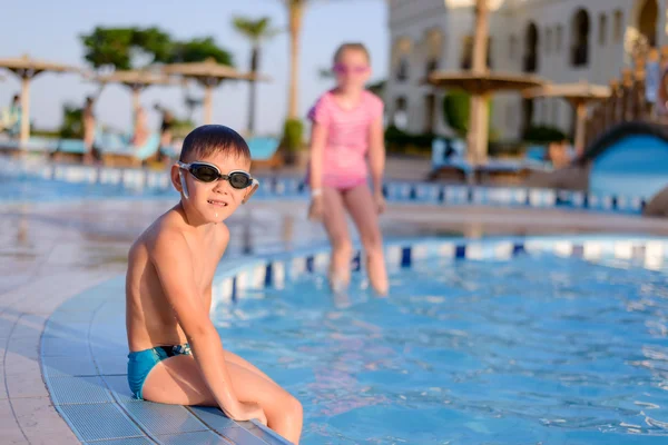 Young boy sitting at the side of a pool — Stok fotoğraf