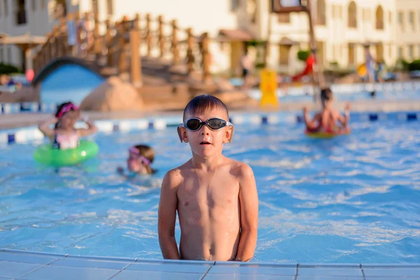 Young boy sitting at the side of a pool — Stok fotoğraf