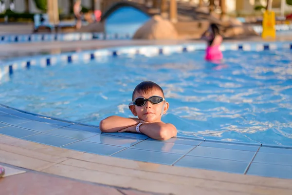 Young boy sitting at the side of a pool — 스톡 사진