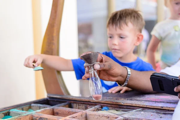 Small boy filling a glass bottle with pigments — Stock Photo, Image