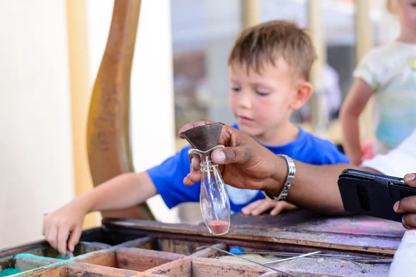 Small boy filling a glass bottle with pigments — Stock Photo, Image