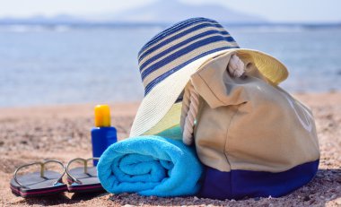 Plaj çantası ve güneşli ıssız plajda güneş şapka