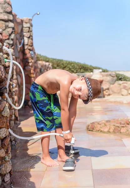 Jongen uit zee zand op een buitendouche spoelen — Stockfoto