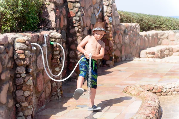 Junge spült bei einer Außendusche Meeressand ab — Stockfoto