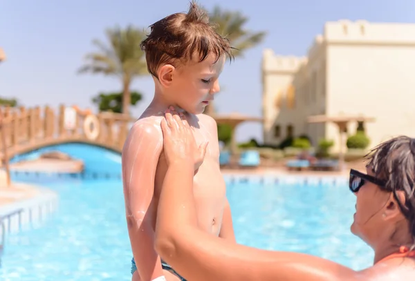 Mother rubbing in sunscreen on her son — Stok fotoğraf