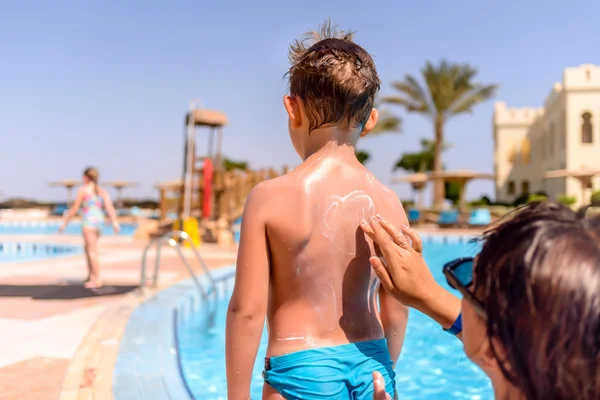 Responsible mother rubbing sunscreen on her son — Stock Photo, Image