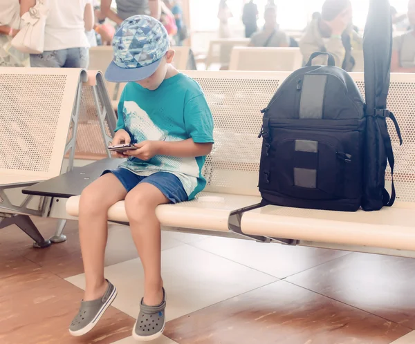 Little boy sitting in an airport departure hall — Stockfoto