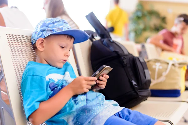 Little boy sitting in an airport departure hall — Stockfoto