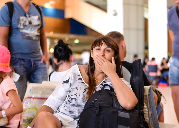 Скучная женщина зевает, ожидая своего полета. — стоковое фото